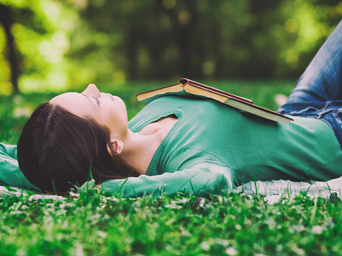 Woman lounging in the grass with a book