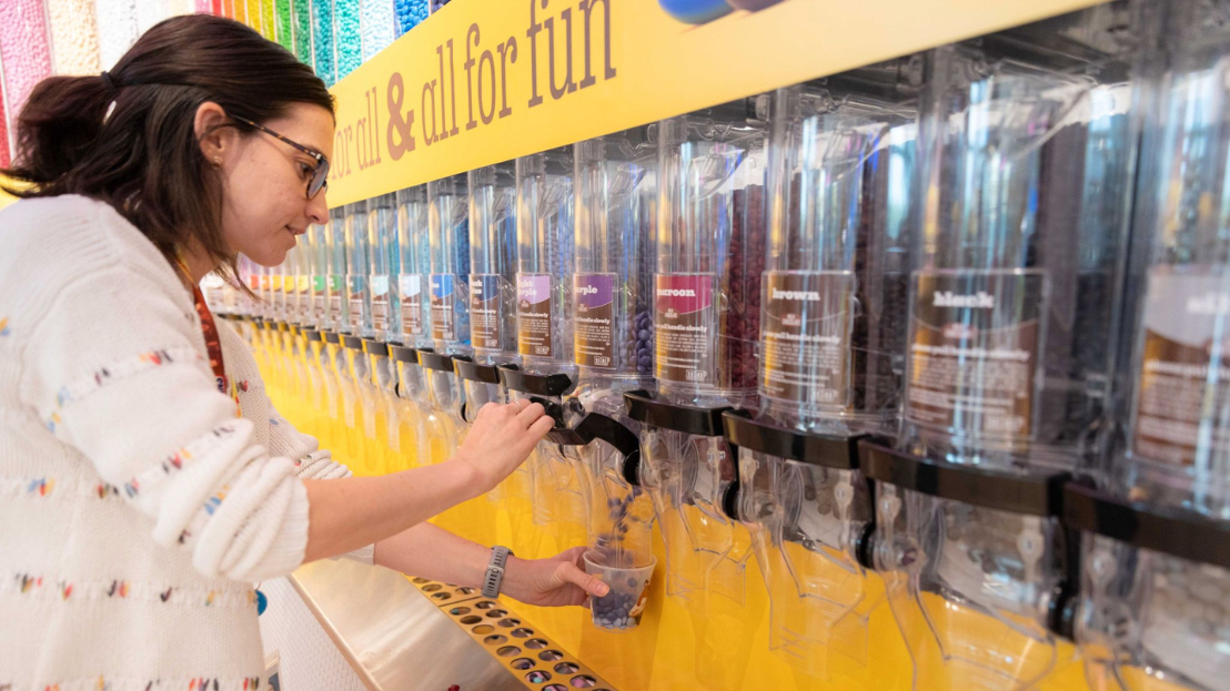A woman refilling a bulk M&M's container