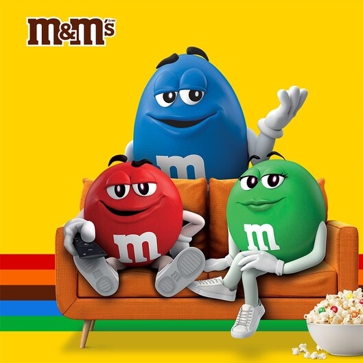 M&M'S characters on a couch with a bowl of popcorn