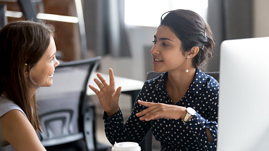 Two women talking to each other in the office