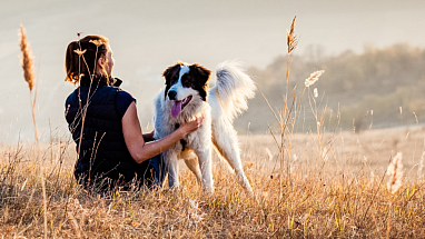 Woman sitting in a field with her dog