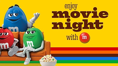 M&M'S characters on a couch with a bowl of popcorn
