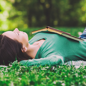Woman lounging in the grass with a book