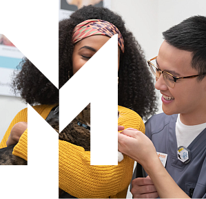 Woman at the vet holding a cat and smiling