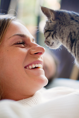 A woman smiling while petting a kitten